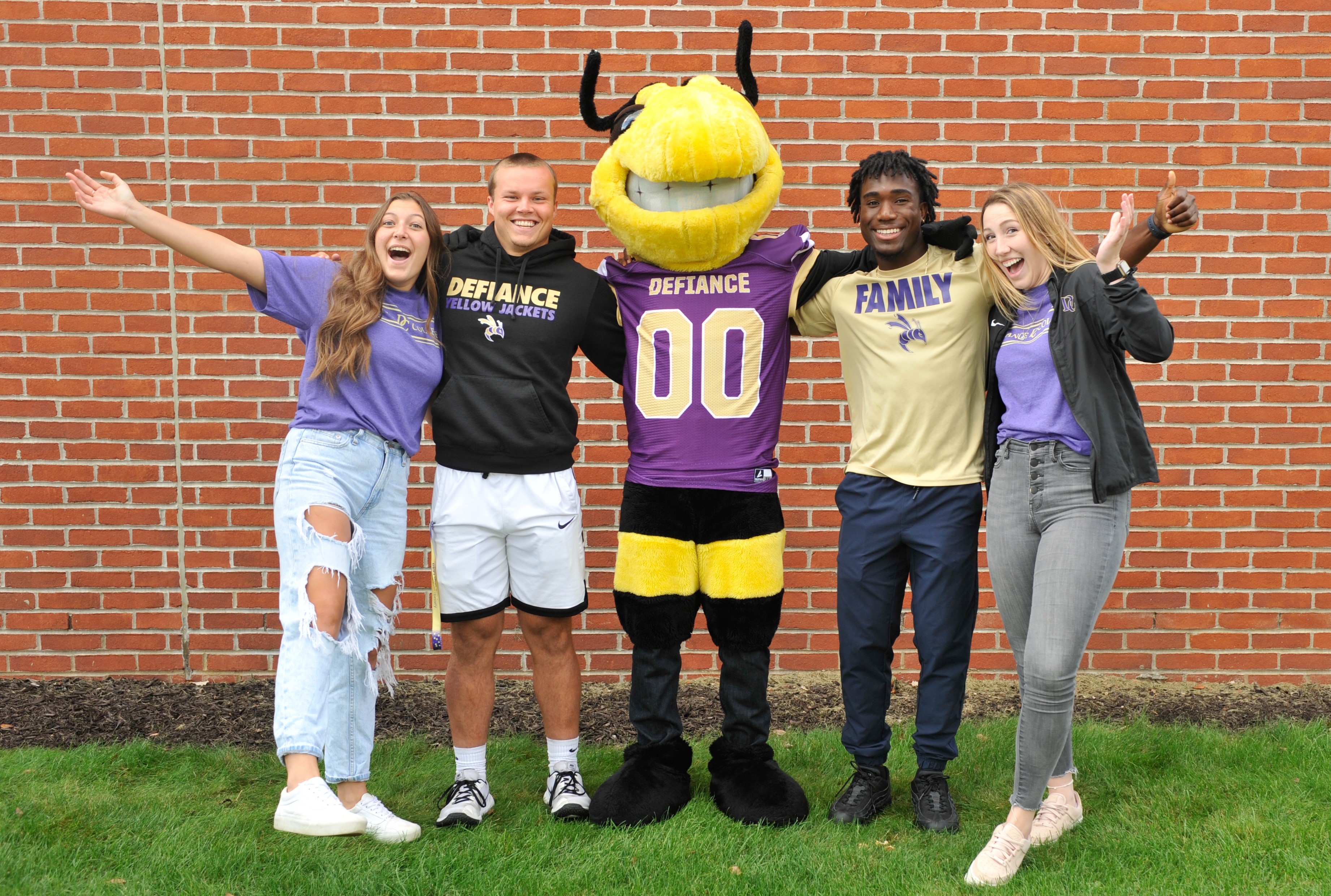 a group of four students with the defiance college mascot