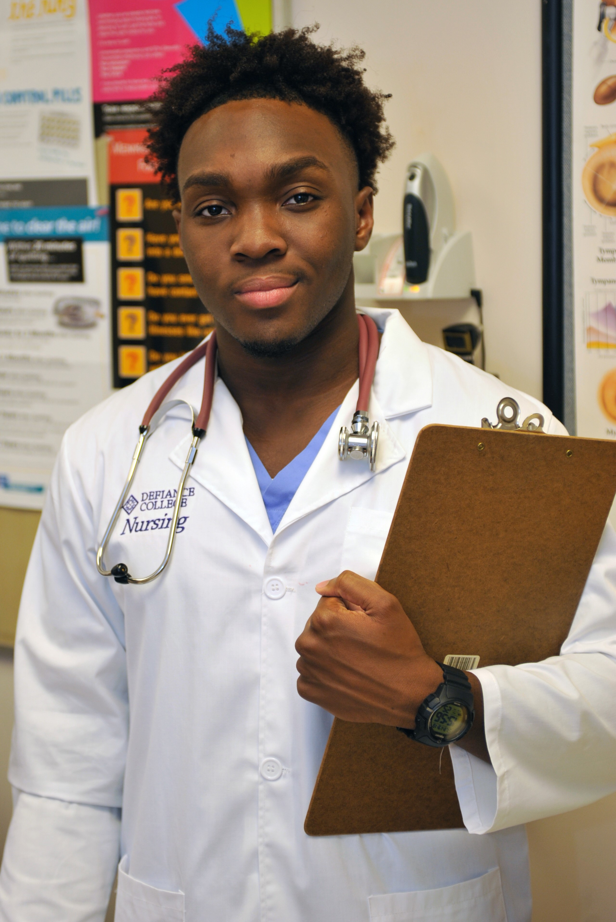 male nursing student with a stethoscope around his neck and a clipboard in his hands