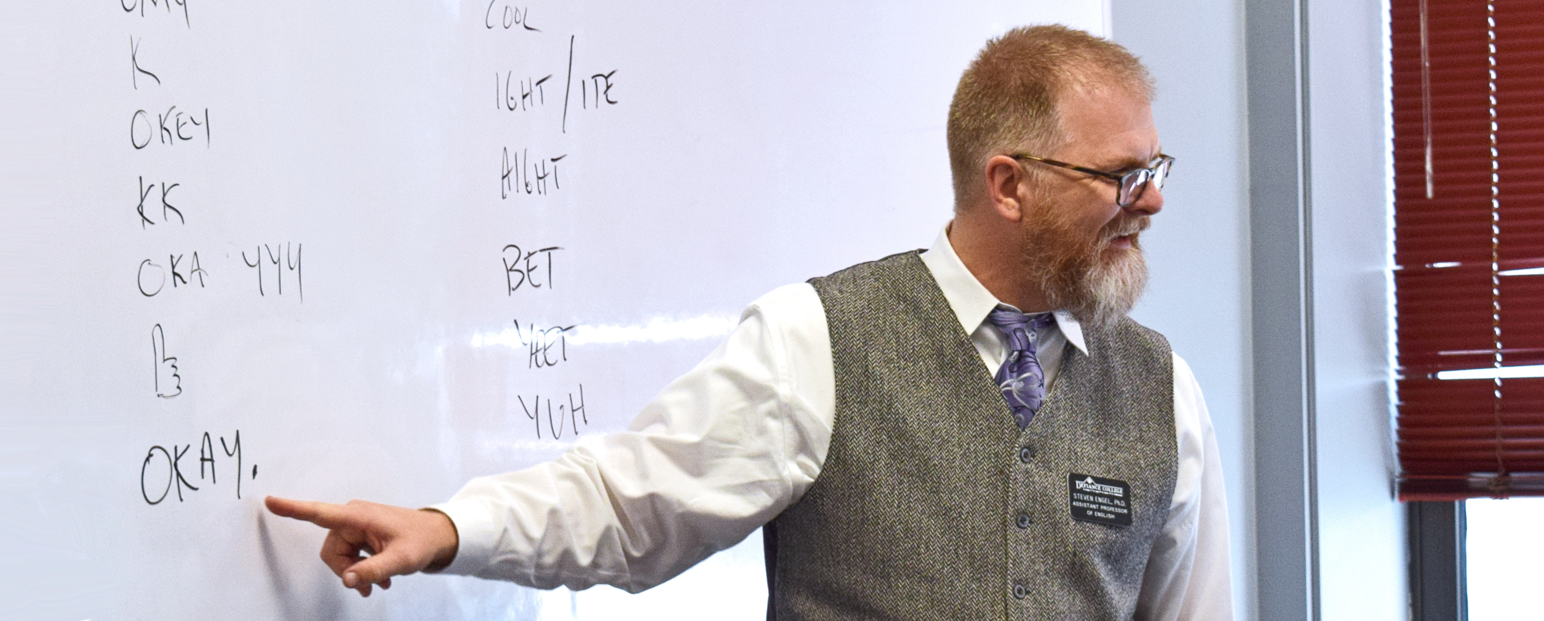 male professor speaking in front of a whiteboard