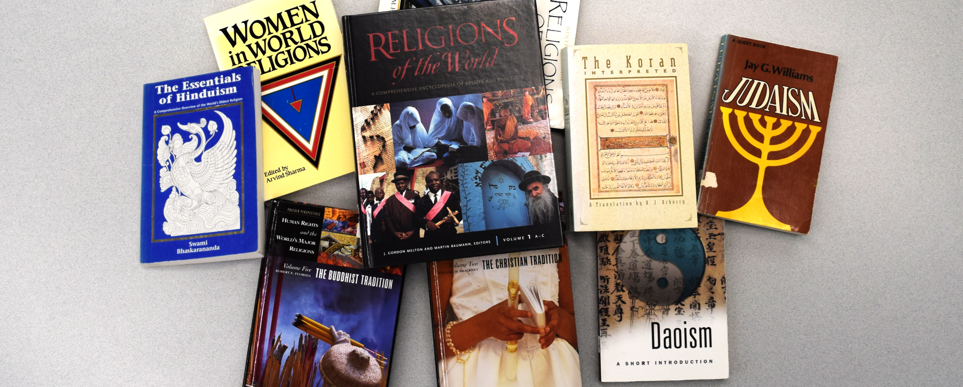 Nine books on various world religions spread out on a table top.