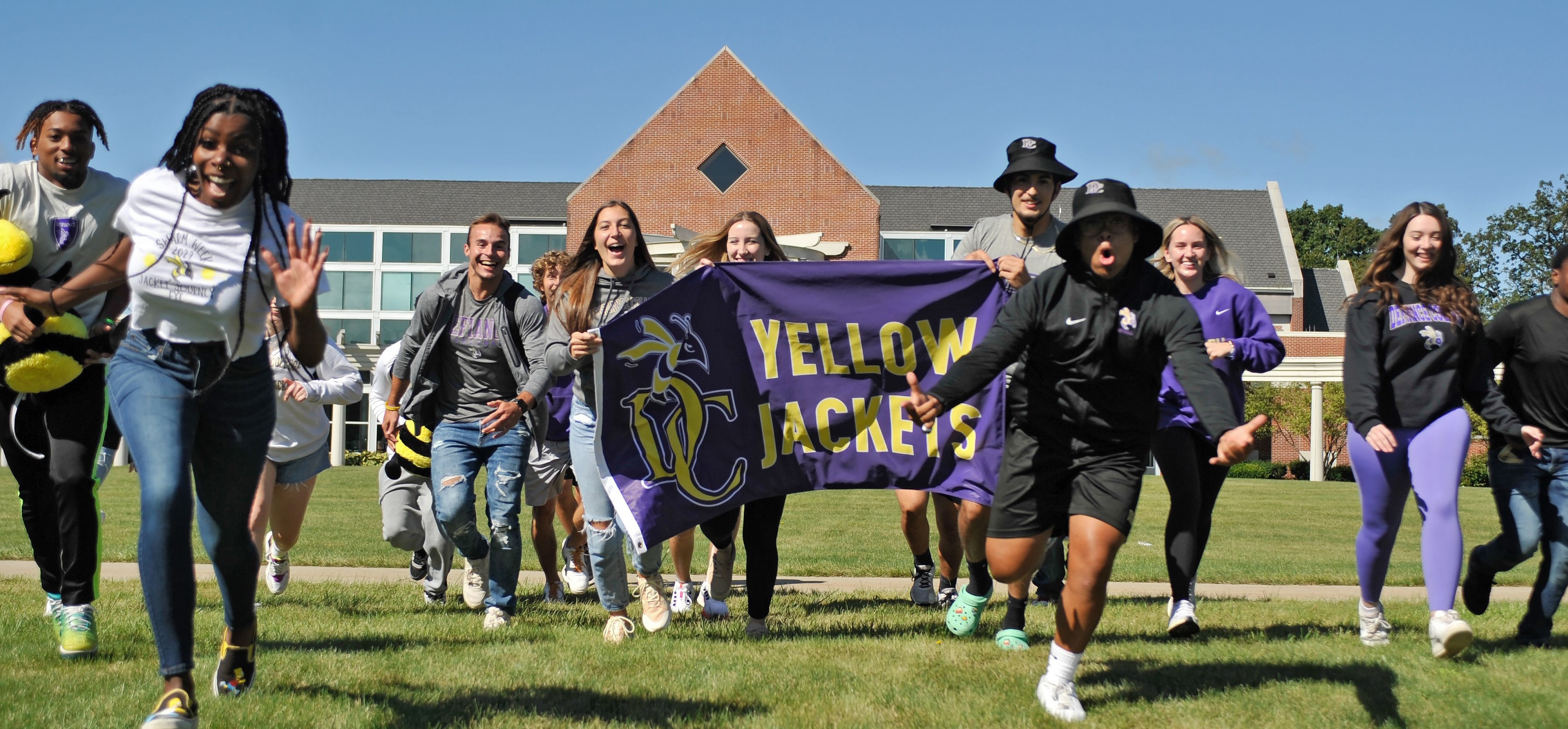 Group of students in front of Serrick Hall running towards the camera laughing